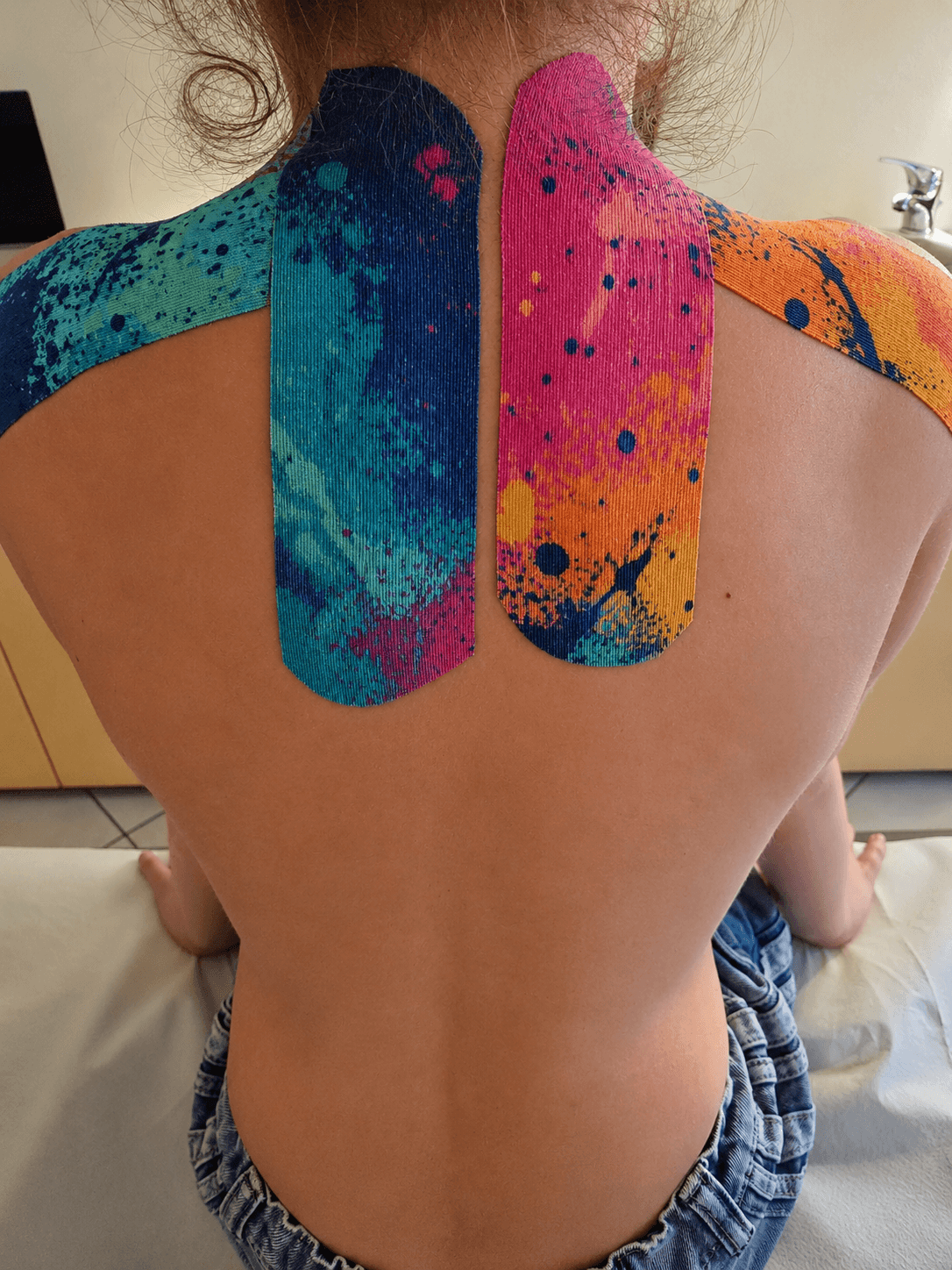 Taping neuro-muscolare applicato sulla schiena di un paziente, in studio